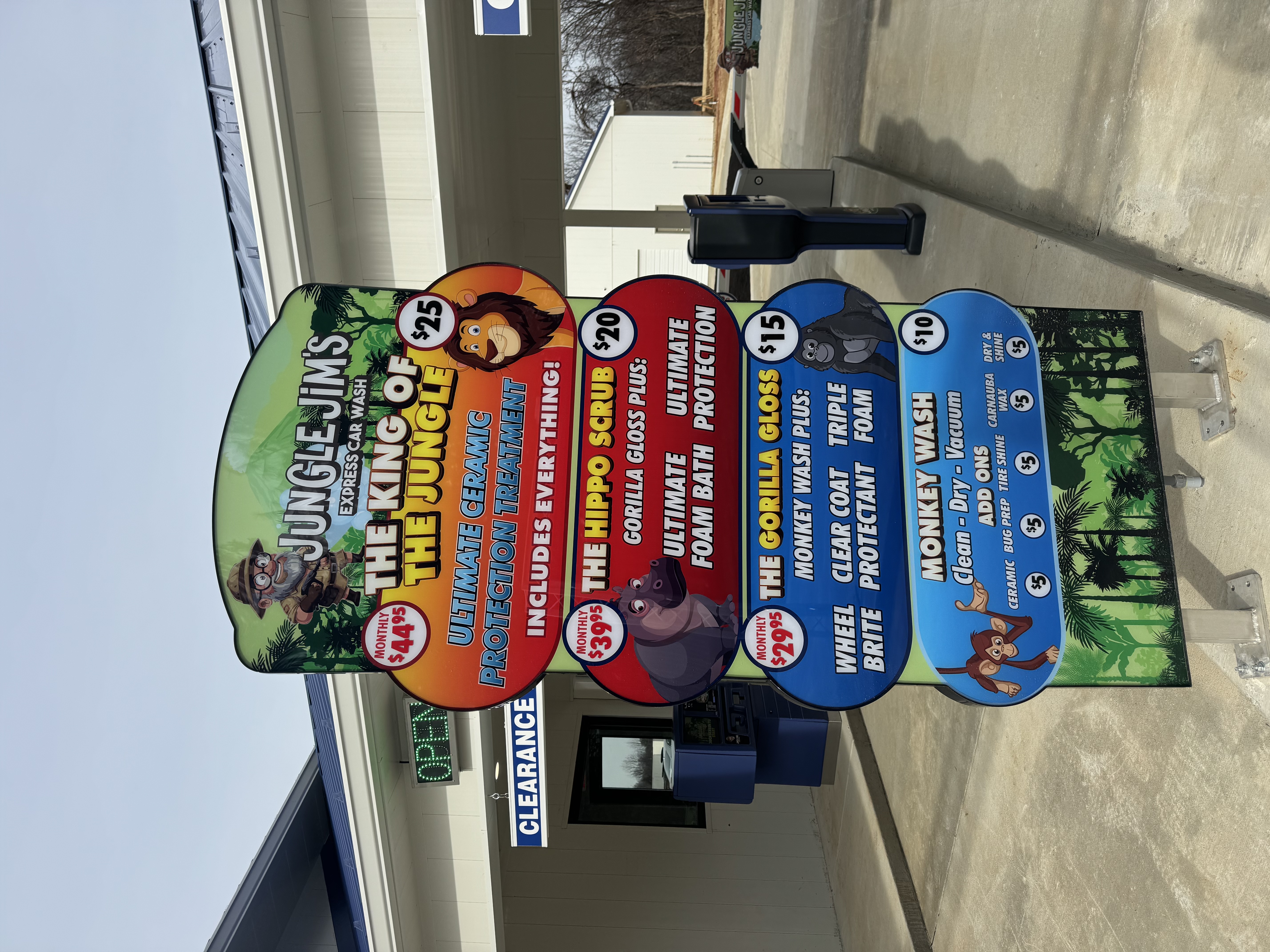 Jungle Jim's Express Car Wash pricing menu sign listing Monkey Wash, Gorilla Gloss, Hippo Scrub, and King of the Jungle wash packages